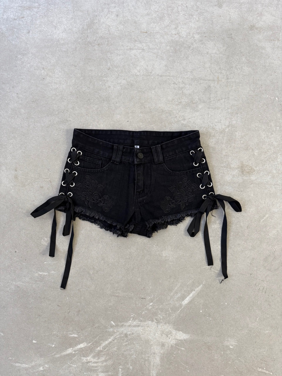 Short negro tiro bajo desflecado con ojalillos y cordones para ajustar costados